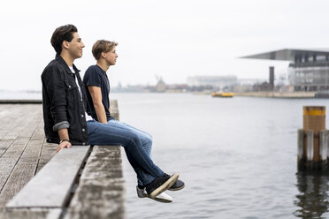 Dänemark, Kopenhagen, zwei junge Männer sitzen am Wasser - AFVF02742