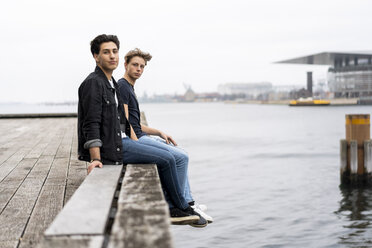 Denmark, Copenhagen, two young men sitting at the waterfront - AFVF02743
