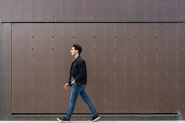 Young man walking along a wall - AFVF02770