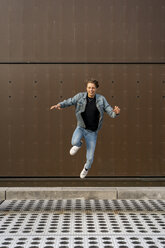 Young man jumping in front of a wall - AFVF02774