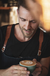 Lächelnde Barista hält eine Kaffeetasse in einem Café - OCMF00420