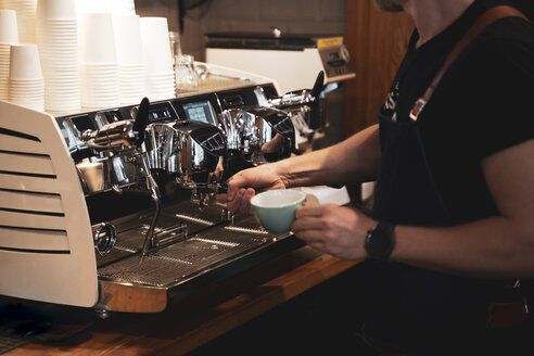 Nahaufnahme eines Barista bei der Zubereitung eines Kaffees in einem Café - OCMF00421