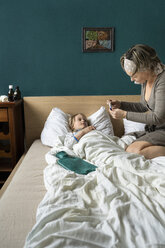 Mutter misst die Temperatur ihrer kranken Tochter, die im Bett liegt - PSIF00253