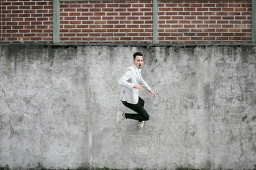 Businessman jumping on a wall - KMKF00861