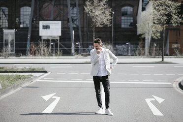 Businessman standing on road with left and right arrows - KMKF00866