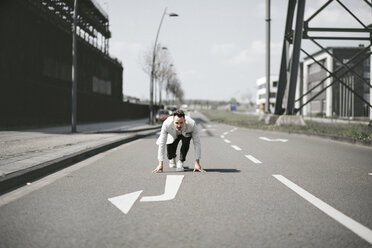 Businessman in starting position on a road with arrow - KMKF00867