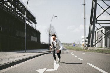 Businessman in starting position on a road with arrow - KMKF00868