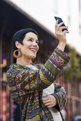 Lächelnde, modische junge Frau macht ein Selfie in der Stadt - JSMF00965