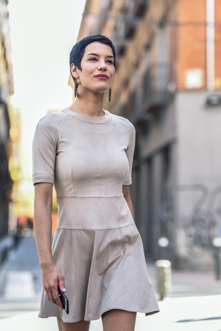 Modische junge Frau in einem Kleid beim Spaziergang in der Stadt, lizenzfreies Stockfoto