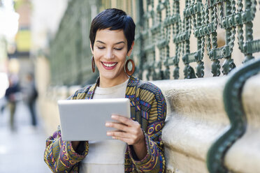 Smiling fashionable young woman using tablet outdoors - JSMF00986