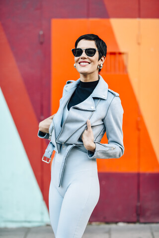 Lächelnde modische junge Frau mit bunten städtischen Hintergrund, lizenzfreies Stockfoto