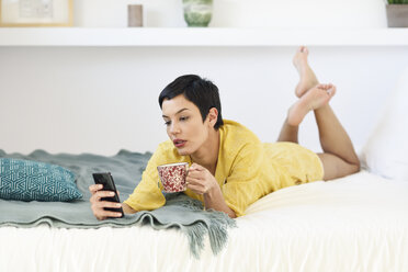 Junge Frau benutzt Mobiltelefon im Bett - JSMF01030