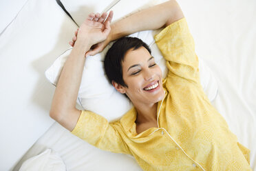 Lächelnde junge Frau im Bett liegend - JSMF01034