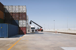 Crane lifting cargo container on truck on industrial site - AHSF00161