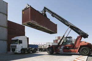 Kran hebt Frachtcontainer auf Lastwagen auf einem Industriegelände - AHSF00167