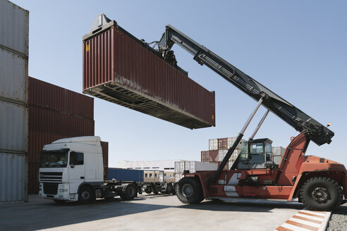 Crane lifting cargo container on truck on industrial site - AHSF00167