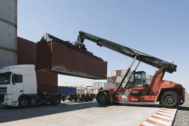 Kran hebt Frachtcontainer auf Lastwagen auf einem Industriegelände - AHSF00168