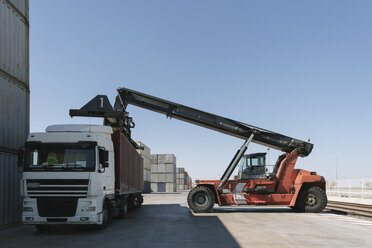 Kran hebt Frachtcontainer auf Lastwagen auf einem Industriegelände - AHSF00170