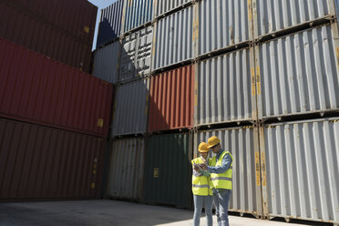 Arbeiter mit Tablet vor Frachtcontainern auf einem Industriegelände - AHSF00179