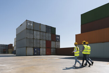 Workers walking together near stack of cargo containers on industrial site - AHSF00195