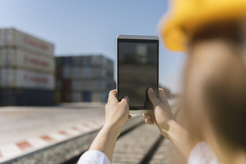 Close-up of female worker holding tablet on railway near to cargo containers on industrial site - AHSF00200