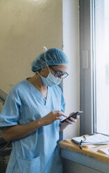 Ärztin mit Smartphone im Krankenhaus, Vorbereitung auf eine Operation - JCMF00043