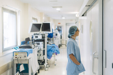 Female doctor standing in hospital corridor, preparing for surgery - JCMF00046