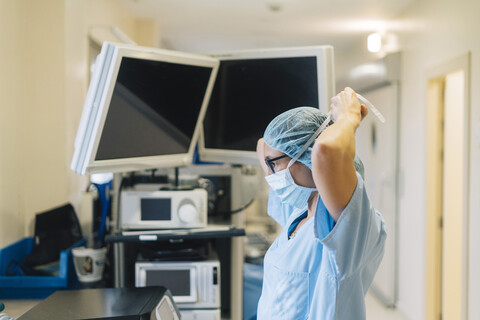 Ärztin, die eine chirurgische Maske bindet und sich auf eine Operation vorbereitet, lizenzfreies Stockfoto