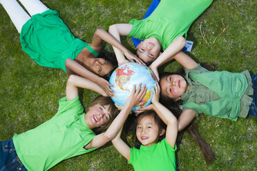 Children laying in grass around globe - BLEF00130