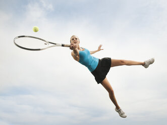 Kaukasische Frau, die in der Luft springt und Tennis spielt - BLEF00149