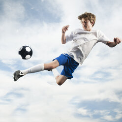 Caucasian teenager kicking soccer ball in mid-air - BLEF00153