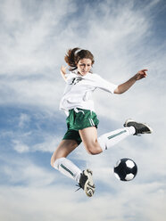 Caucasian teenager kicking soccer ball in mid-air - BLEF00154