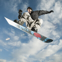 Kaukasischer Mann auf Snowboard in der Luft - BLEF00159