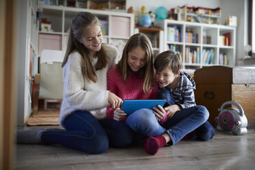 Geschwister, die zu Hause mit ihren digitalen Tablets spielen und auf dem Boden sitzen - RBF07018