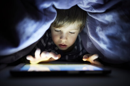 Kleiner Junge spielt heimlich mit seinem digitalen Tablet, versteckt unter der Bettdecke - RBF07029