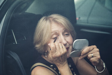 Ältere Frau trägt Make-up im Auto auf - MAMF00611
