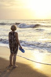 Italien, Sizilien, ältere Frau genießt den Sonnenuntergang am Strand - MAMF00615