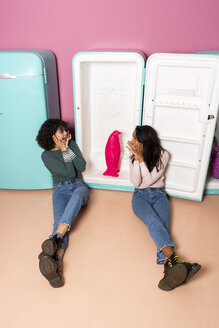 Zwei aufgeregte junge Frauen in einem Indoor-Vergnügungspark haben Spaß mit einer Pinguinfigur im Kühlschrank - AFVF02813