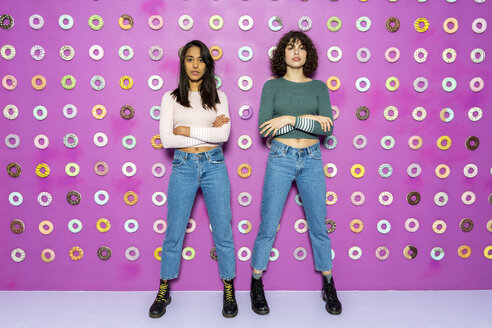 Zwei junge Frauen posieren in einem Indoor-Vergnügungspark mit Donuts an der Wand - AFVF02817