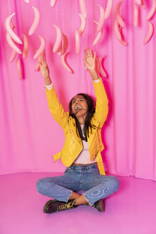 Young woman screaming at an indoor theme park with dangling pink bananas - AFVF02822
