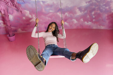 Portrait of happy young woman on a swing at an indoor theme park - AFVF02825