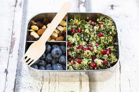 Lunchbox with bulgur herbs salad with pomegranate seeds, taboule, blueberries and trail mIx stock photo