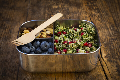 Lunchbox mit Bulgur-Kräutersalat mit Granatapfelkernen, Taboulé, Blaubeeren und Trailmix, lizenzfreies Stockfoto