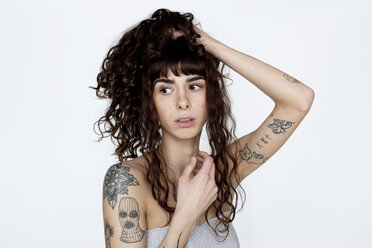 Portrait of tattooed young woman with hand in hair - FLLF00124