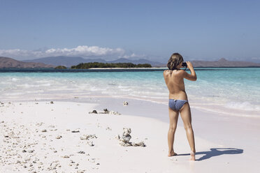 Indonesien, Komodo-Nationalpark, Mädchen am Strand beim Fotografieren - MCF00137