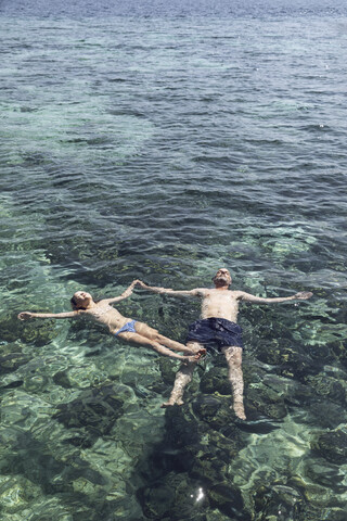 Indonesien, Komodo-Nationalpark, Vater und Tochter schwimmen im Meer, lizenzfreies Stockfoto