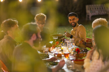 Fröhliche Freunde beim Abendessen auf einer Gartenparty - CAIF23207