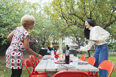 Freundinnen bereiten den Tisch für das Abendessen vor Gartenparty - CAIF23208