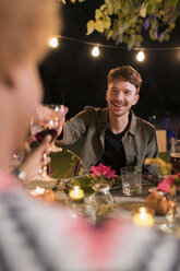 Glücklicher Mann stößt mit einem Weinglas beim Abendessen auf eine Gartenparty an - CAIF23209