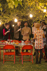 Freunde unterhalten sich unter Bäumen bei einer Gartenparty zum Abendessen - CAIF23251